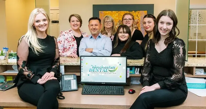 A photo of a group of dental professionals is posing together in a bright, welcoming office setting.
